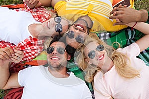 Happy people group young friends lying down on picnic blanket outdoor