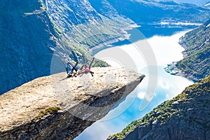 Happy people relax in cliff during trip Norway. Trolltunga hiking route