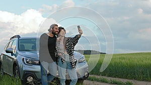 Happy people using mobile for selfie near car at countryside