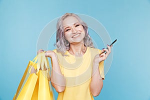 Happy person with shopping bags and phone in the studio.