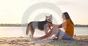 Happy pet owner relaxing and hugging her dog on the beach in summer