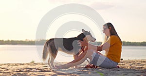 Happy pet owner relaxing and hugging her dog on the beach in summer