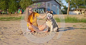 Happy pet owner relaxing and hugging her dog on the beach in summer