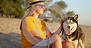 Happy pet owner relaxing and hugging her dog on the beach in summer