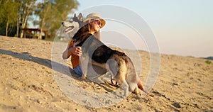 Happy pet owner relaxing and hugging her dog on the beach in summer