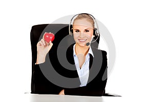 Happy phone operator woman holding heart toy