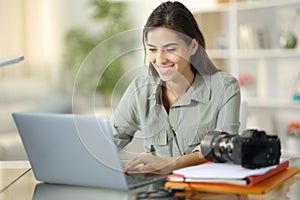 Happy photographer checking laptop at home