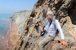 Happy photographer traveler sitting on the edge of a cliff.