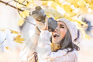 Happy photographer in a winter cap photoshoots outdoors in colorful fall nature