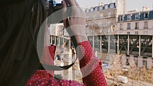 Happy photographer woman taking a photo of morning Eiffel Tower view in Paris with vintage camera, tilt up close-up shot