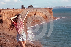 Happy pinup girl outdoor portrait. Travel vacation fun summer woman dancing in freedom with arms up happy over Black sea. Carefree