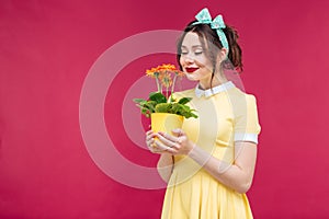 Happy pinup girl stamding and smelling orange flower in pot