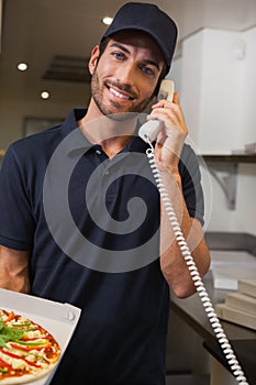 Happy pizza delivery man taking an order over the phone