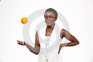 Happy playful african woman thowing orange up in the air