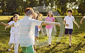 Happy playful kids friends playing active outdoor games in the summer park.