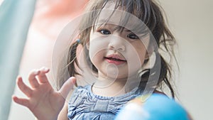 Happy playful toddler looking at globe ball on bed in bedroom at home