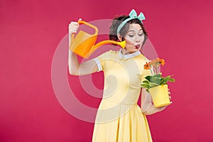 Happy playful young woman watering flowers in pot