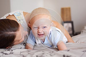 Happy, playing and a baby with mother on a bed for bonding, laughing and fun together. Smile, love and a family, child