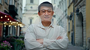 Happy pleased confident man standing outdoor joyful male tourist stands in city center looking at camera smiling asian