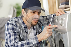 Happy plumber repairing washing machine