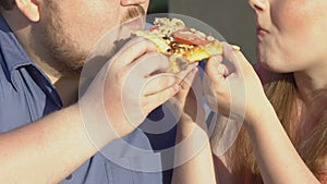 Happy plus size couple eating tasty pizza slice together, overweight, fast food