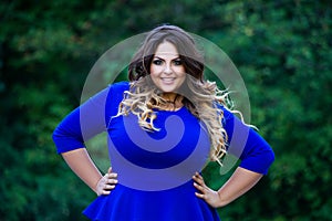 Happy plus size fashion model in blue dress outdoors, fat woman with beauty makeup and hairstyle