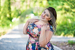 Happy plus size fashion model in floral dress outdoors, beautiful fat woman with beauty makeup and hairstyle