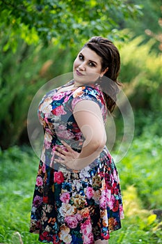 Happy plus size fashion model in floral dress outdoors, beautiful fat woman with beauty makeup and hairstyle
