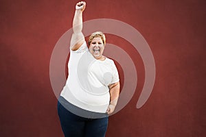 Happy plus size woman celebrating with winning gesture outdoors in the city - Focus on face