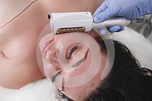 Happy plus size woman getting facial endospheres massage photo
