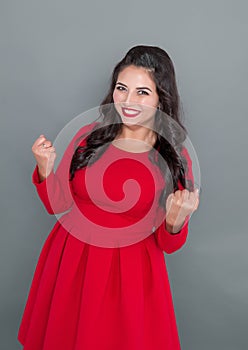 Happy plus size woman in red dress showing yes gesture on gray