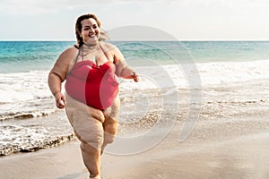 Happy plus size woman running on the beach - Curvy overweight model having fun during vacation in tropical destination