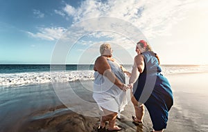 Happy plus size women dancing on the beach - Curvy overweight girls having fun during vacation in tropical destination