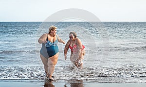 Happy plus size women having fun on the beach during summer vacation