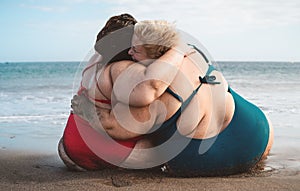 Happy plus size women having fun embracing on the beach during vacation summer holidays