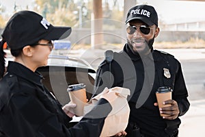 Happy policewoman with paper cup giving