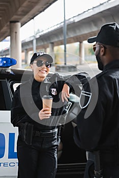Happy policewoman with paper cup looking