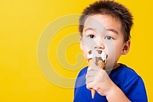 Kid cute little boy attractive laugh smile playing holds and eating sweet chocolate ice cream waffle cone