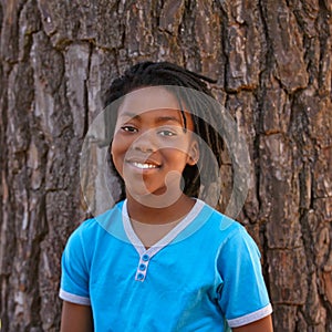 Happy portrait, black child and tree in fashion, hairstyle or childhood for outdoor nature. Face of young African, male