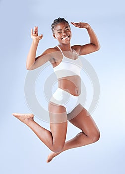 Happy, portrait and black woman in lingerie jump in studio for body positivity, freedom and acceptance on blue