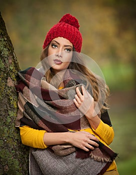 Happy Portrait fashion of a beautiful young Caucasian woman with a red cap and scarf and yellow pullover in autumn park,red green photo