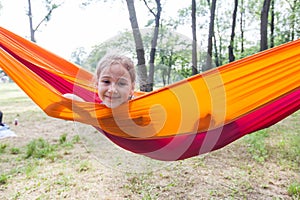 Happy portrait of little girl relax on hammock in forest