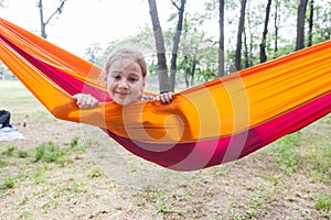 Happy portrait of little girl relax on hammock in forest