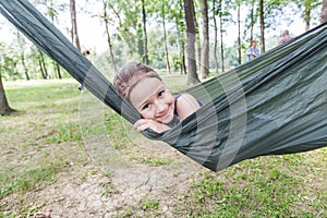 Happy portrait of little girl relax on hammock in forest