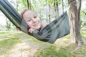 Happy portrait of little girl relax on hammock in forest