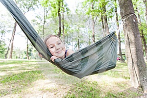 Happy portrait of little girl relax on hammock in forest
