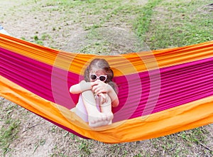 Happy portrait of little girl relax on hammock in forest