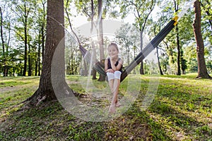 Happy portrait of little girl relax on hammock in forest