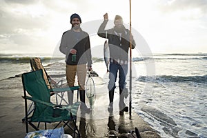 Happy, portrait and men fishing at ocean with pride for tuna catch on pier at sunset. Fisherman, friends and smile