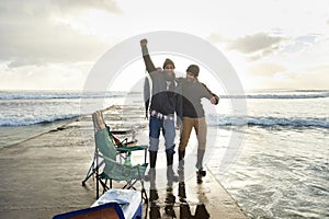 Happy, portrait and people fishing at ocean with pride for tuna catch on pier at sunset. Fisherman, friends and smile